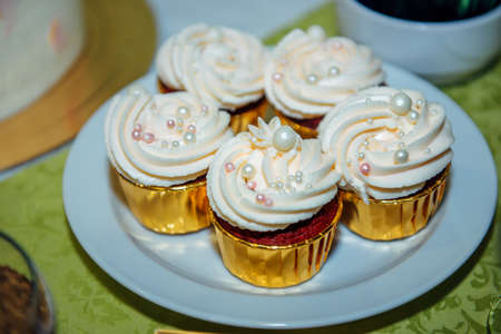 Delicious cupcakes with whipped cream. Exquisite sweets at a festive banquet. Dessert table, close-up.の写真素材