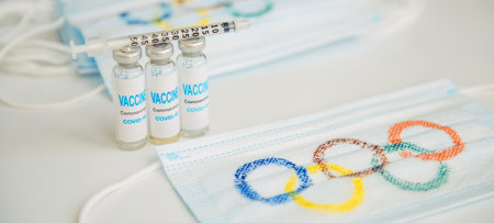 Safety of sports competition during covid19 pandemic. Mandatory vaccination of athletes at the Olympics. Mask, vaccine, syringe on white background. Novosibirsk, Russia - 06.01.2022.のeditorial素材