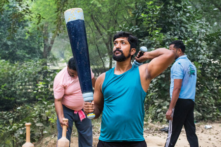 Unidentified Indian wrestlers do exercise by lifting their traditional equipments near ganga Ghat in...