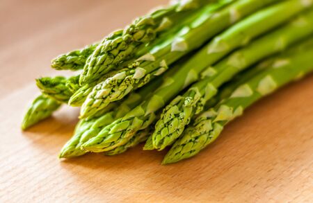 Bunch of green asparagus on a wooden board. Close-up with blured background.の写真素材