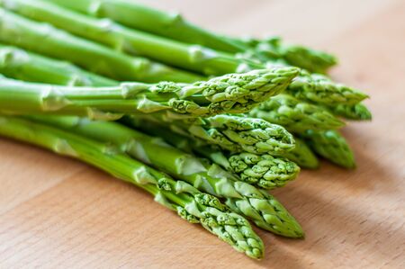 Bunch of green asparagus on a wooden board. Close-up with blured background.の写真素材