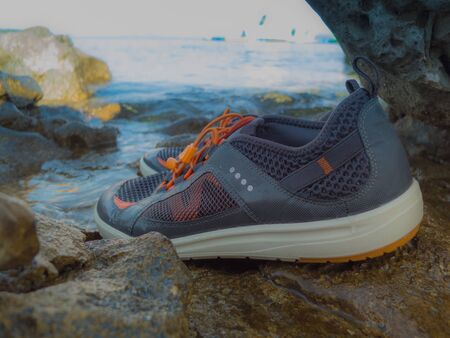 Pair of wet swimming/sailing shoes on a stony coast.の写真素材