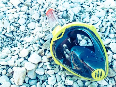 Wet snorkelling mask laying on white stones, retro effect.の写真素材