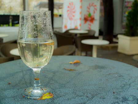 Wine glas forgotten on a table, filled with rain water.の写真素材