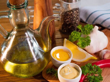Close-up of the mayonnaise ingredients on rustic wood background and olive wood cutting board.の写真素材