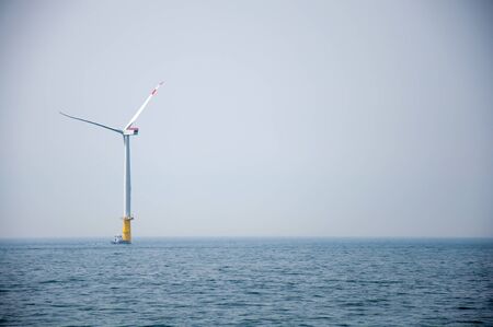 Offshore wind farm with one wind mills in the north sea and a supply boat.の写真素材