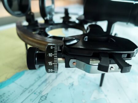Sextant on a chart table, with a nautocal charts in background.の写真素材