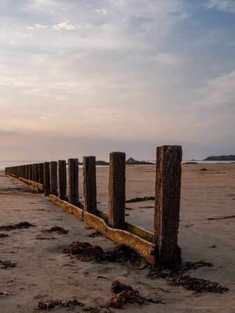 A wooden breakwater on the sand beach at the beautiful sunset.の写真素材