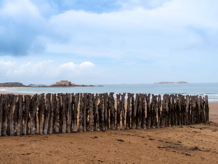 An old wooden breakwaters on the coastline with the fortress on the background.の写真素材