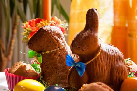 A table decorated for celebration of the easter, with coloured eggs and baked rabbit and sheep. With a focus on a sheep.の写真素材