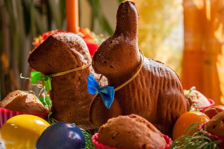 A table decorated for celebration of the easter, with coloured eggs and baked rabbit and sheep. With a focus on a rabbit.の写真素材