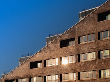 A diagonal picture of the modern office building in sunset light with a blue sky.の写真素材