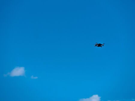 A quadrocopter flying with a blue sky in background.の写真素材