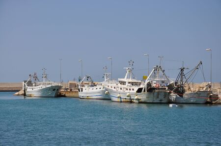 Several old fishing boats alongside in harbour on a sunny summer day.の写真素材