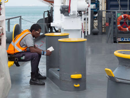 Panama City, Panama, 10 March, 2013: A worker on board of the vessel sitting and reading bible during the working break.のeditorial素材