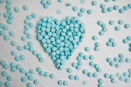 Heart made of blue pills isolated on white backgroundの写真素材