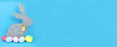 Easter, soft, gray hare and eggs are plain, multi-colored on a blue background.の写真素材