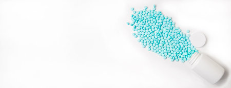 Banner. Blue pills are scattered from a white jar on a white background.の写真素材