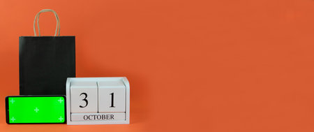 Banner. October 31 on wooden calendar, green screen phone and paper black bag