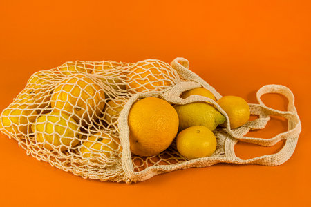 Citrus fruits orange, lemon, mandarin lie in cotton bag, string bag .の写真素材