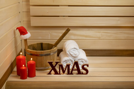 Sauna. Wooden bucket, burning candles, towels and santas hat, Xmas inscriptionの写真素材
