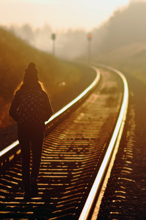 Young girl walking along railroad at sunsetの写真素材
