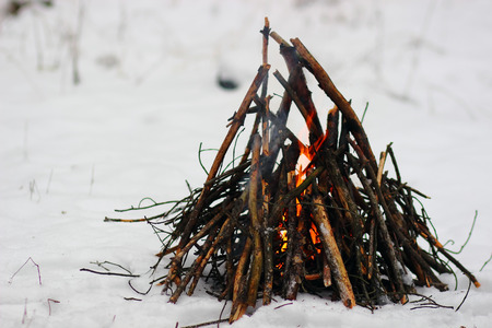 Camp fire in winter time, surrounded by snow.