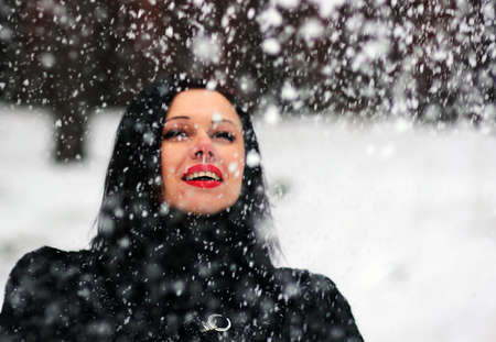 Cute young woman playing with snow in fur coat outdoorsの写真素材