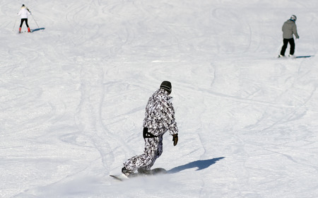 Skiers and snowboarders on a snowy slopeの写真素材