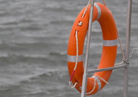 Red lifebuoy hanging on railings of rescue boatの写真素材
