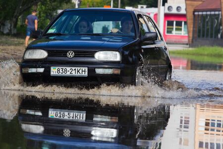 CHERKASSY, UKRAINE- JUNE 5, 2016: cars driving on a flooded road during a flood caused by heavy rain, in Cherkassy.のeditorial素材