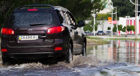 CHERKASSY, UKRAINE- JUNE 5, 2016: cars driving on a flooded road during a flood caused by heavy rain, in Cherkassy.のeditorial素材