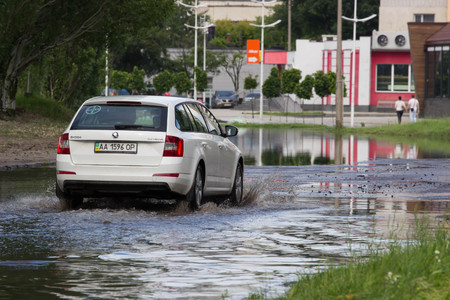 CHERKASSY, UKRAINE- JUNE 5, 2016: cars driving on a flooded road during a flood caused by heavy rain, in Cherkassy.のeditorial素材