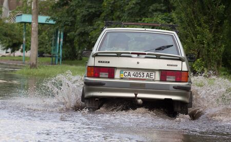 CHERKASSY, UKRAINE- JUNE 5, 2016: cars driving on a flooded road during a flood caused by heavy rain, in Cherkassy.のeditorial素材
