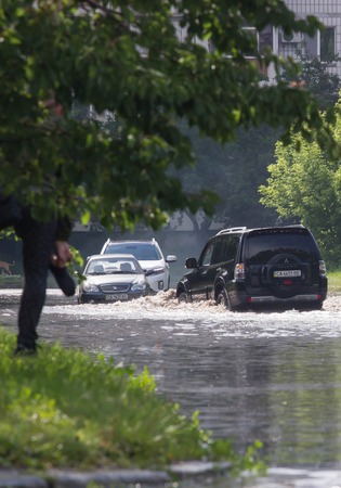 CHERKASSY, UKRAINE- JUNE 5, 2016: cars driving on a flooded road during a flood caused by heavy rain, in Cherkassy.のeditorial素材