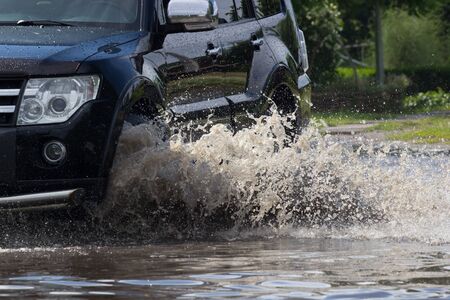 cars driving on a flooded road during a flood caused by heavy rain,