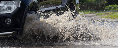 cars driving on a flooded road during a flood caused by heavy rain,