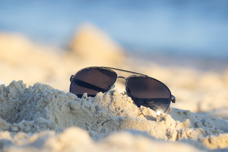 Top view of sunglasses on the beach near the blue sea. Sand and glasses. Summer vacation actually relaxing, .の写真素材