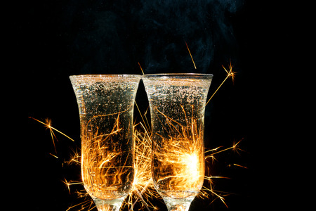 Glasses of champagne and sparklers on bright background with sparklers.の写真素材
