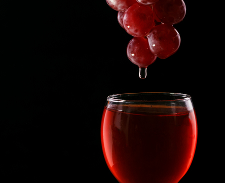 Wine glass and red grapes on a black backgroundの写真素材
