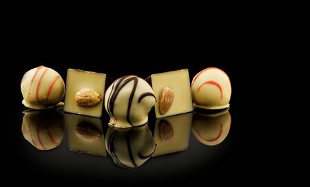 Chocolate candies assortment on black background with reflection