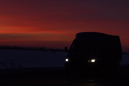 silhouette of the car traveling on the road to a beautiful colorful sunsetの写真素材