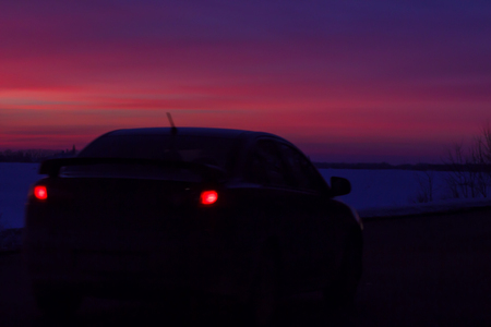 silhouette of the car traveling on the road to a beautiful colorful sunsetの写真素材