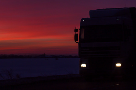 silhouette of the car track traveling on the road to a beautiful colorful sunsetの写真素材