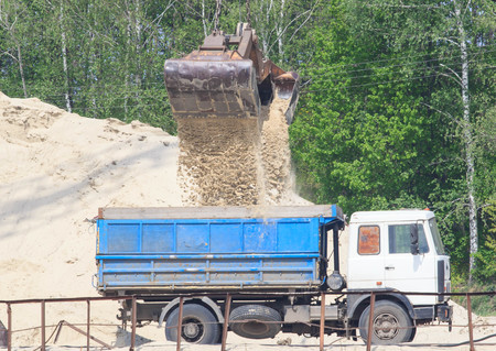 wheel loader excavator machine loading dumper truck at sand quarryの写真素材