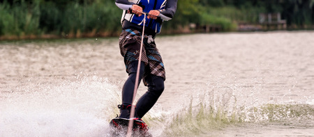 male athlete rides on a wakeboard on lake in summer.の写真素材