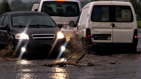 Car traffic in a heavy rain on a flooded city roadの写真素材