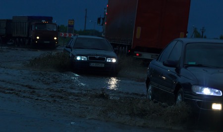 SHPOLA, UKRAINE- JULY 28, 2017: cars driving on a flooded road during a flood caused by heavy rain, in Shpolaのeditorial素材