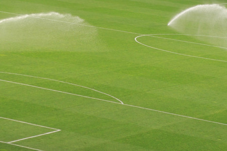 Sprinkler system working on fresh green grass on football (soccer) stadiumの写真素材