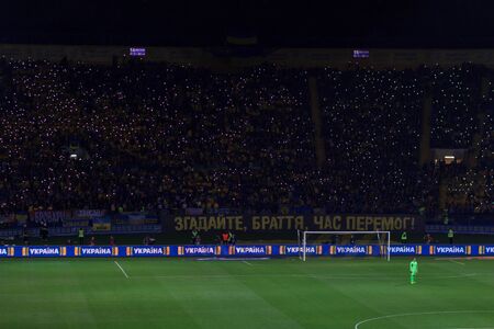 KHARKIV, UKRAINE - SEPTEMBER 2, 2017: Ukrainian fans with huge flag of Ukraine and logo of Football...